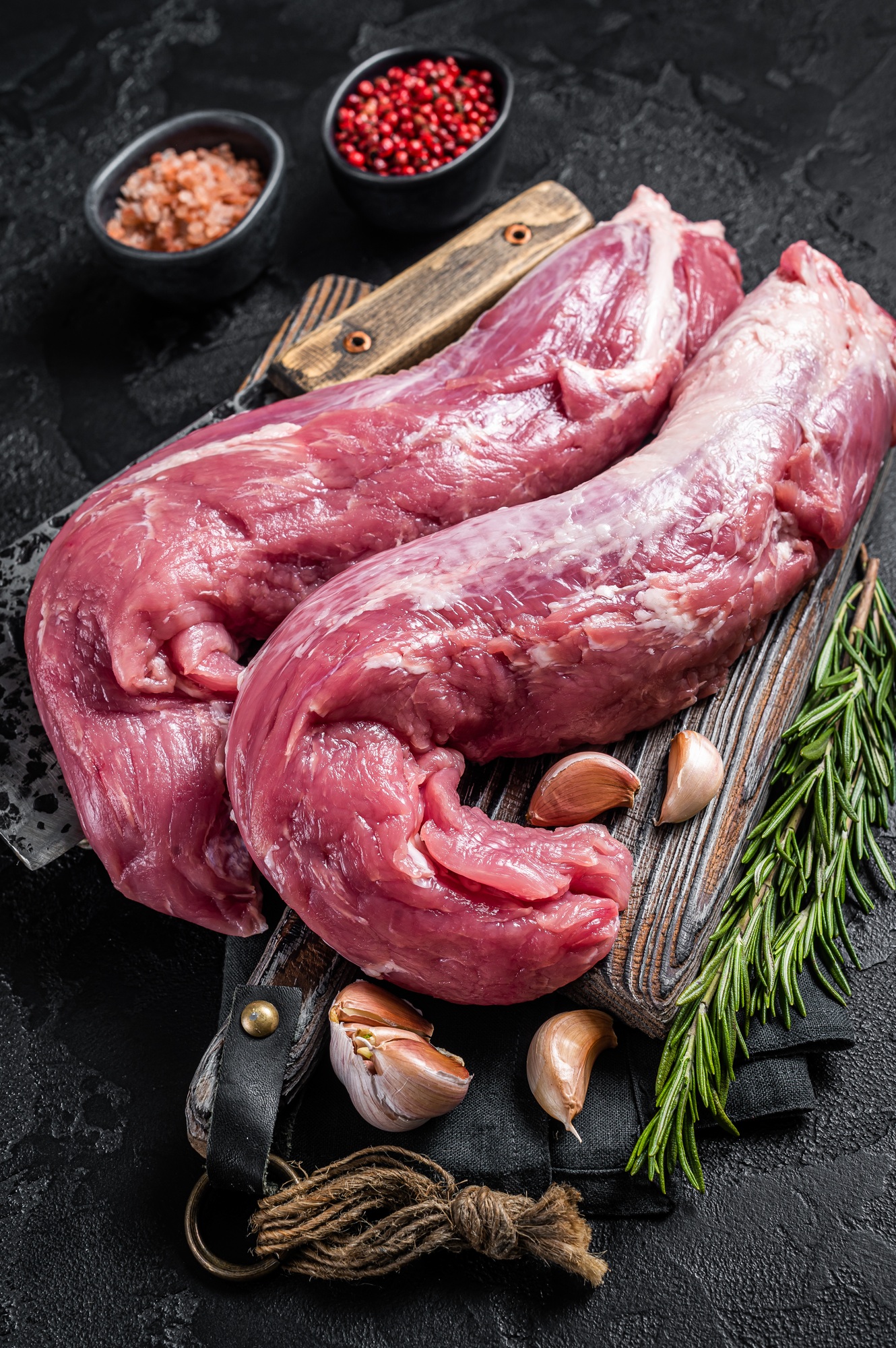 Pork tenderloin meat, raw uncooked fillet on butcher board with meat cleaver